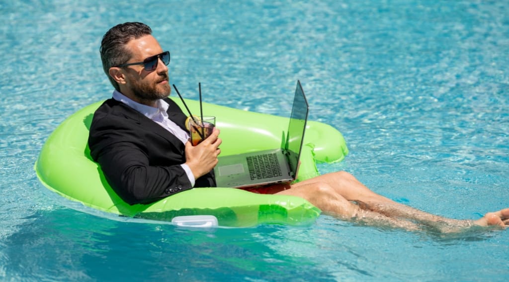 A businessman sits in a swimming pool rubber ring on his laptop